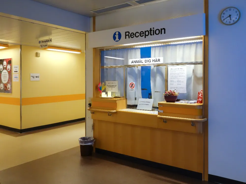 Banque d'accueil d'un service hospitalier avec comptoir en bois clair et vitrage