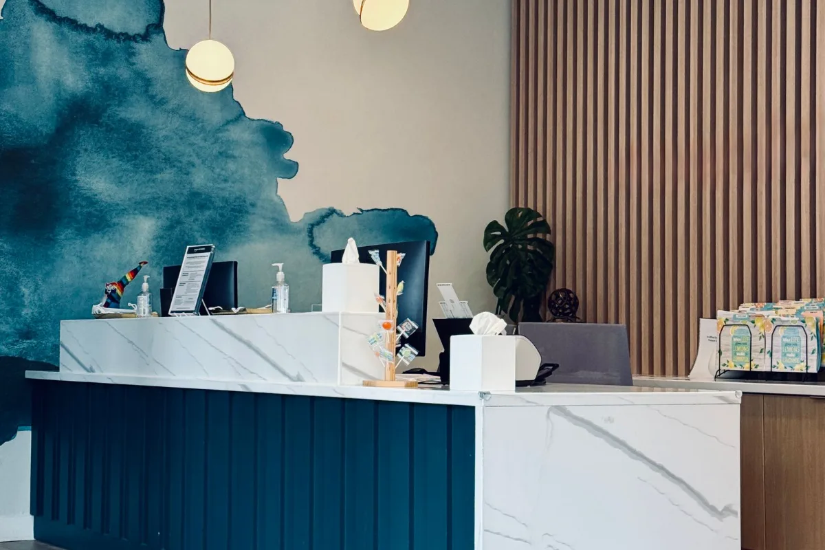 Banque d'accueil moderne avec plan en pierre blanche veinée et mur en lames de bois